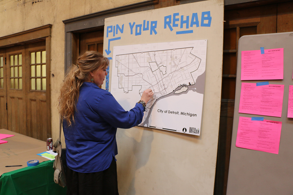 A woman adds a pin to a map on the wall